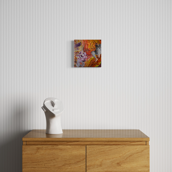 The artwork 'See No Evil' by Mary Younkin features vibrant swirls of orange, pink, and gray acrylic paint with collage elements on an 8x8 wood panel, creating an abstract expressionist composition. The piece is shown displayed above a wooden cabinet alongside a minimalist white ceramic sculpture.