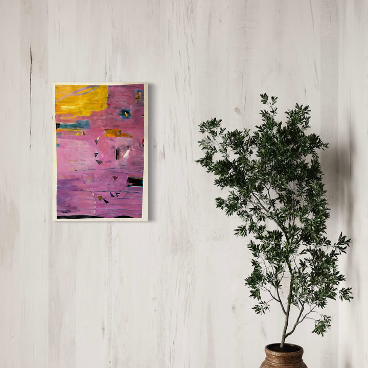 The artwork 'Abstract 11.24' by Owen Brown features vibrant pink and magenta tones dominating the composition, with a striking yellow accent in the upper corner. Bold brushstrokes and dynamic marks create texture across the acrylic painting, while scattered dark elements add depth and contrast to the 35x24 inch piece on watercolor paper. Displayed against a white wall beside a potted plant. By Owen Brown.