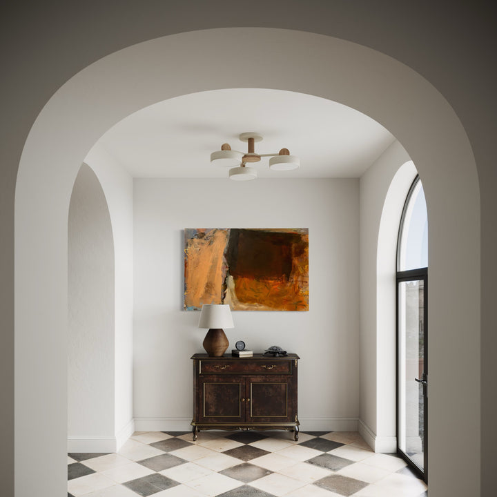 The artwork 'Bend to the Light' by Christopher Blyth features bold abstract composition in warm amber and deep brown tones on canvas, displayed through an elegant arched doorway. The painting hangs above a vintage dark wood cabinet on a striking diamond-patterned floor, creating a harmonious blend of modern art and classic interior architecture.