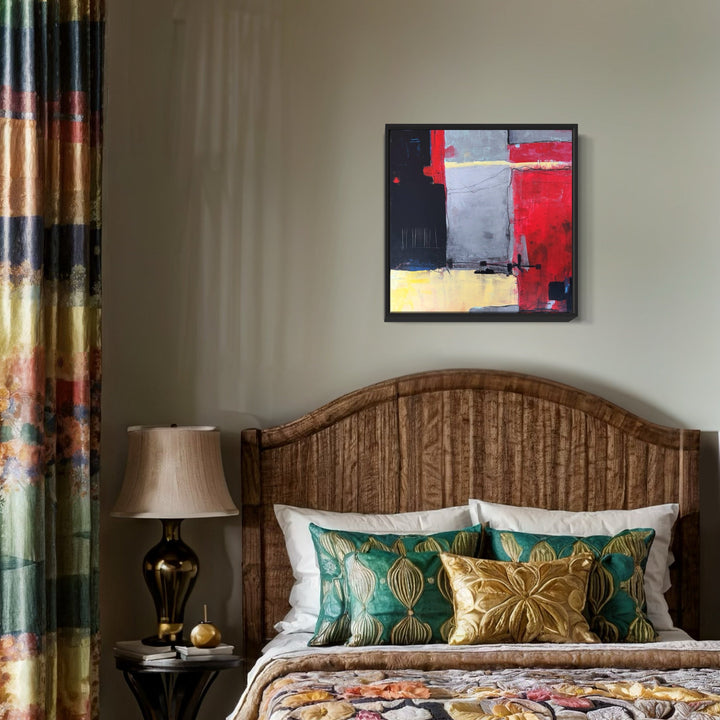 The artwork 'Between Giving and the Shield' by Karen L. Burns features bold geometric blocks of vibrant red and steel grey, accented with textured yellow sections. The abstract composition uses acrylic and mixed media to create dynamic contrasts and layered textures, mounted in a black frame against a light wall, demonstrating contemporary expressionist style.