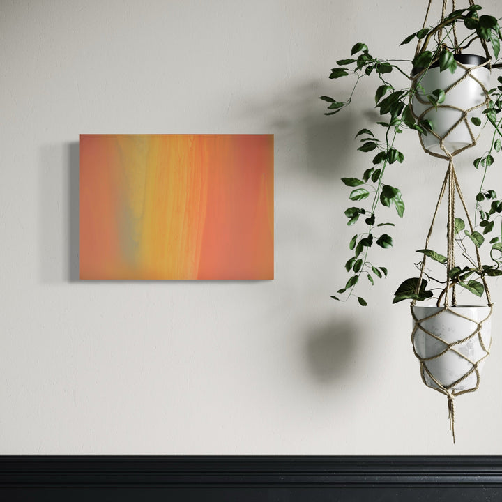 The artwork 'Carrying and Soaring 13' by Willy Bo Richardson features vertical color gradients transitioning from warm coral orange to vibrant yellow, with subtle green undertones. The abstract composition on wood panel combines acrylic and oil paints to create smooth, seamless color transitions. Displayed on a white wall beside hanging plants.