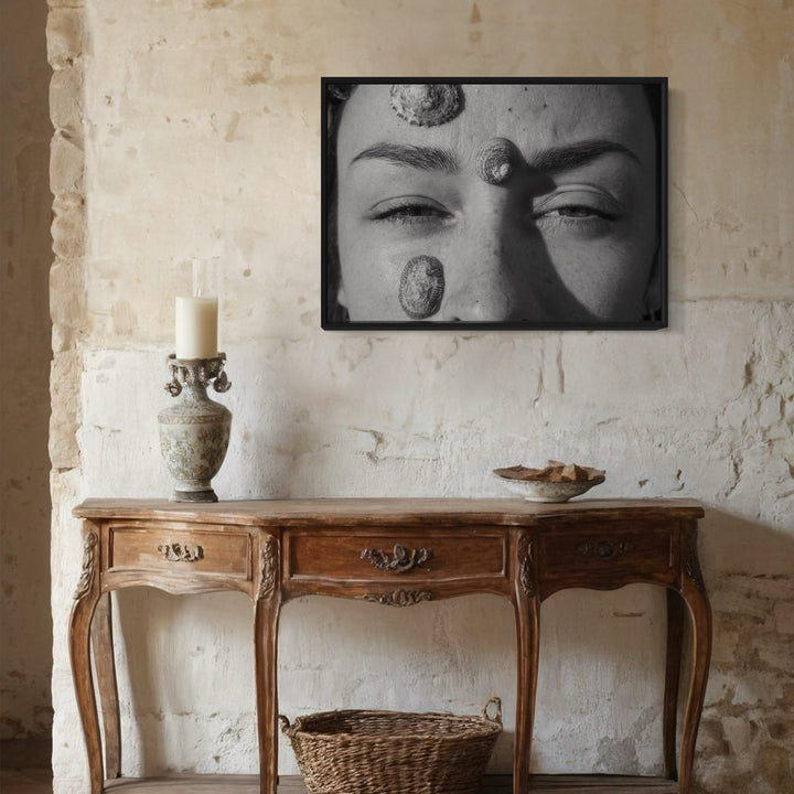 The artwork 'Communion I' by Eunice Pais showcases a dramatic black and white photograph above an antique French console table. The framed artwork depicts an intimate close-up composition with abstract organic elements, mounted on a textured cream wall. Below sits a carved wooden console with ornate details, accessorized with a stone candleholder and decorative basket.