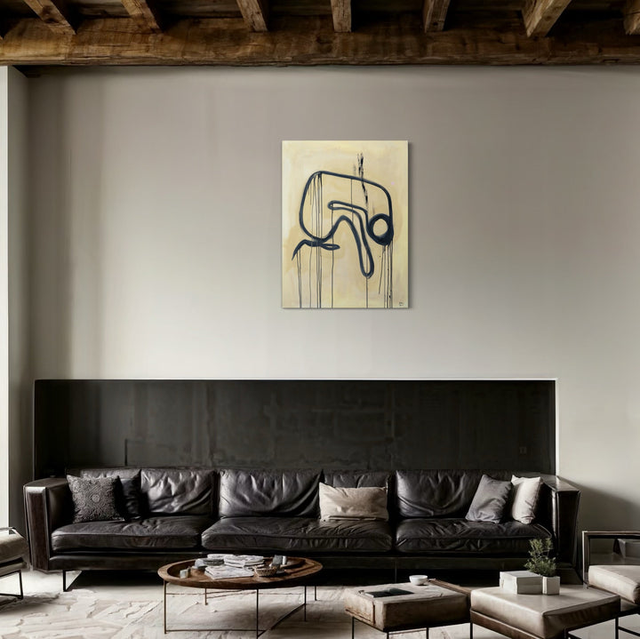 The artwork 'Emotions - Overwhelmed yet Hopeful' by Hazal Ozturk features a minimalist black line drawing on cream canvas, displaying fluid abstract forms suggesting movement and emotional flow. The piece hangs above a modern black leather sofa, creating striking contrast against light walls in a contemporary living space. Acrylic on canvas, 48x36 inches.