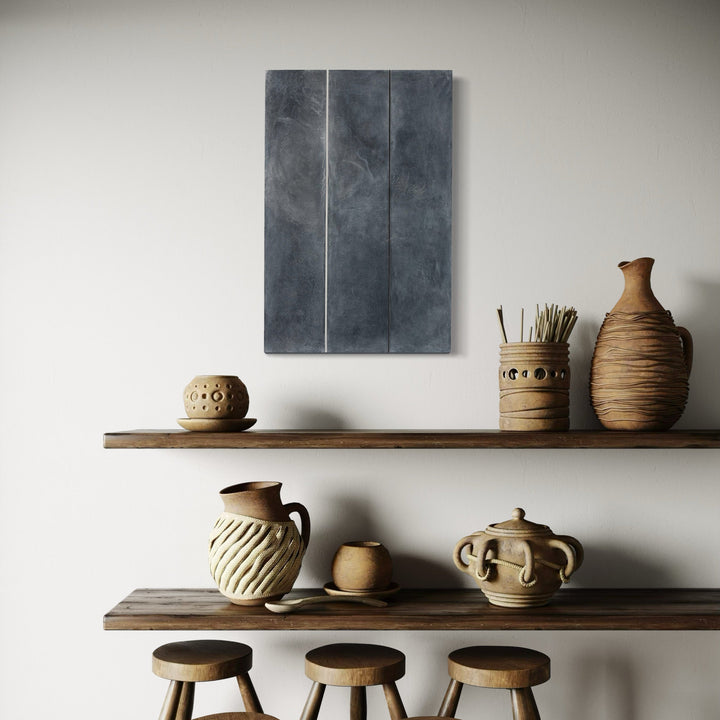 The artwork 'Erasure 31' by Erika Mahr features minimalist vertical lines on a moody charcoal-grey background, rendered in mixed media on panel. Two delicate white lines divide the dark atmospheric surface, creating a subtle geometric composition that contrasts with the textural, cloudy effects achieved through charcoal and paint techniques.