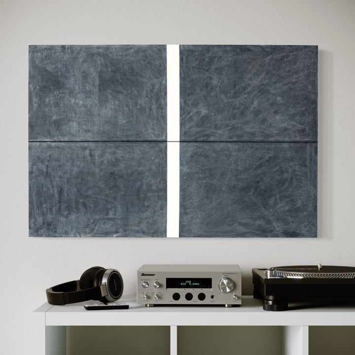 The artwork 'Erasure 39' by Erika Mahr features a minimalist composition of four slate-gray panels divided by crisp white lines, creating a geometric abstract pattern. The textured surface, achieved through charcoal and paint on panel, displays subtle variations in tone and ethereal markings throughout the moody monochromatic piece.