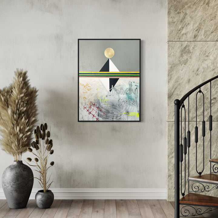 The artwork 'Eternal Soul' by Jodi Fuchs features a minimalist geometric composition with a golden circular moon atop a black triangular mountain. Below, abstract graphite sketches and ethereal acrylic strokes blend with gold leaf accents, creating a mystical landscape in soft grays and whites, highlighted by subtle green stripes. Artwork displayed in sleek black frame.