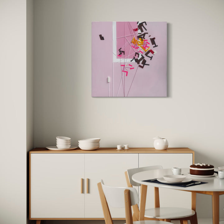 The artwork 'Excentrer Kolyianott' by Philippe Halaburda features abstract geometric shapes and letters scattered dynamically across a soft pink canvas. Black angular forms and pink linear elements create a sense of movement, while yellow accents add vibrant contrast. The 30x30 inch mixed media composition combines modern typography with minimalist design elements, mounted on a gallery-wrapped canvas.