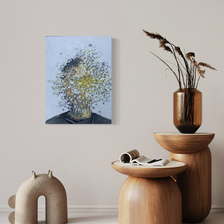 The artwork 'Explosive' by Matthew Cramer features an abstract portrait where the subject's head appears to burst into particles of yellow and blue hues against a light background. The oil painting showcases a dynamic dispersion effect, with specks of color radiating outward from a central point, creating a powerful sense of motion and transformation on the 24x18 inch canvas. By Matthew Cramer.