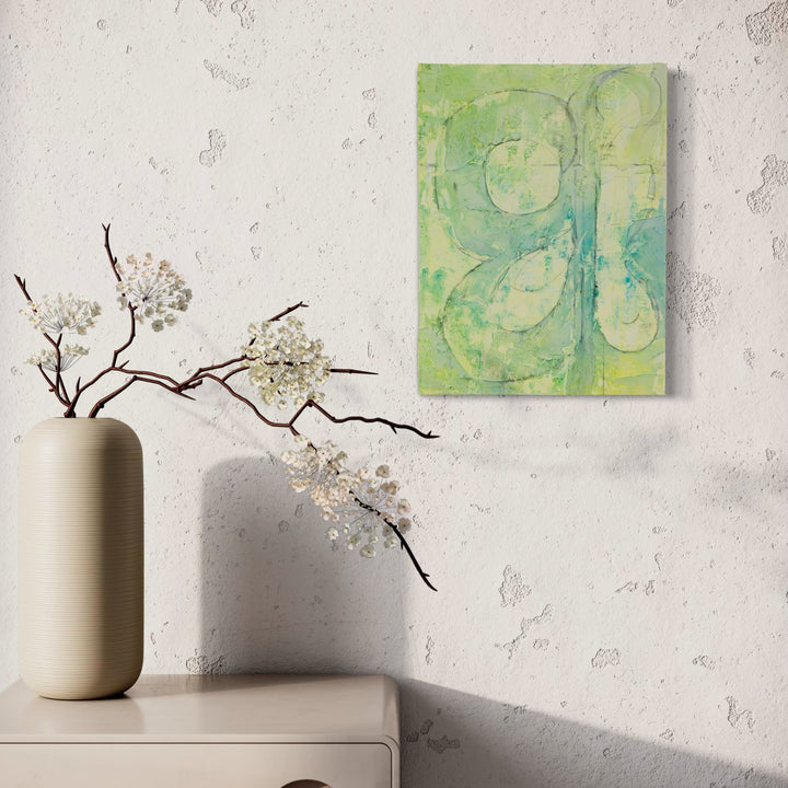 The artwork 'Four Leaf Clover' by Lisa Petker Mintz features abstract circular shapes in soft green and turquoise hues, created with acrylic and charcoal on board. The painting showcases gentle, flowing brushstrokes that form clover-like patterns against a serene mint-colored background, displaying a modern, minimalist approach to botanical art. Artwork by Lisa Petker Mintz.