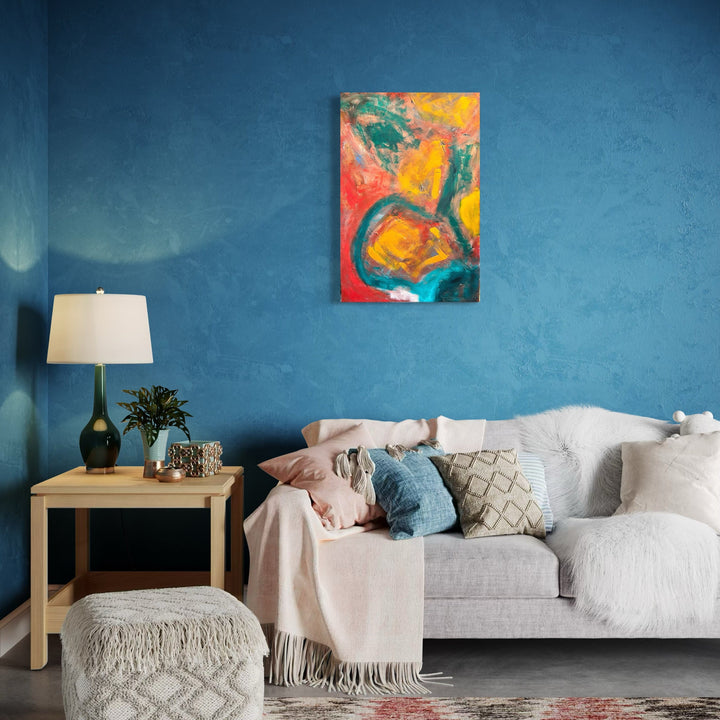 The artwork 'Fragmented' by Genevieve Antonello features bold abstract expressionist strokes in vibrant coral, yellow, and teal hues on board. Dynamic curved shapes and gestural brushwork create a sense of movement across the composition. The oil painting's energetic style and contrasting colors make a striking statement against the deep blue wall where it's displayed.