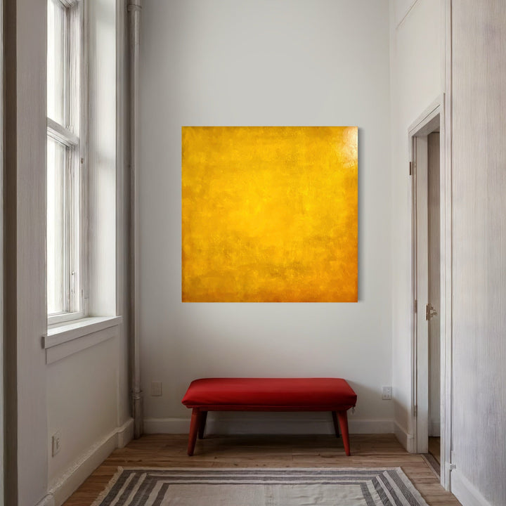 The artwork 'Here Comes the Sun' by Nicole Hitchcock features a vibrant, monochromatic yellow square canvas with subtle textural variations. The 48x48-inch acrylic painting displays a rich golden hue with a weathered, sun-kissed finish, creating depth through varying saturations and brushwork techniques.