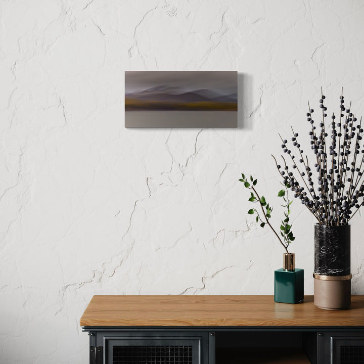 The artwork 'Iceland Highlands' by Neil Shapiro captures a minimalist landscape featuring misty mountains in muted grays and browns, with a subtle golden glow on the horizon. The print on textured Hahnemühle paper presents a serene, atmospheric composition that blends abstract and realistic elements in a panoramic format. Photo by Neil Shapiro.