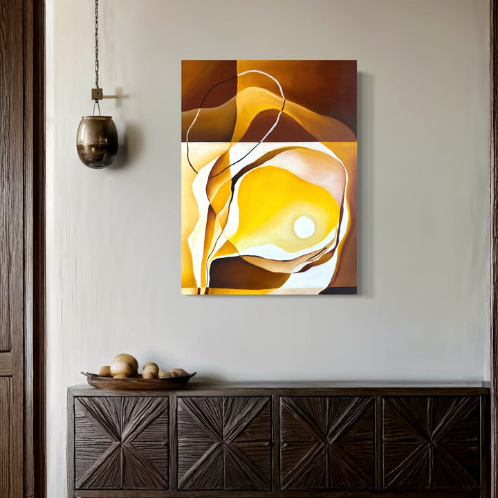 The artwork 'Icarus Blinking' features abstract flowing forms in warm amber and golden tones, with sinuous white lines creating dynamic movement across the composition. Rich chocolate brown edges frame luminous yellow centers, suggesting ethereal atmospheric effects. Oil on panel creates smooth, seamless transitions between colors. Mounted above dark wooden furniture. By Meam Hartshorn.