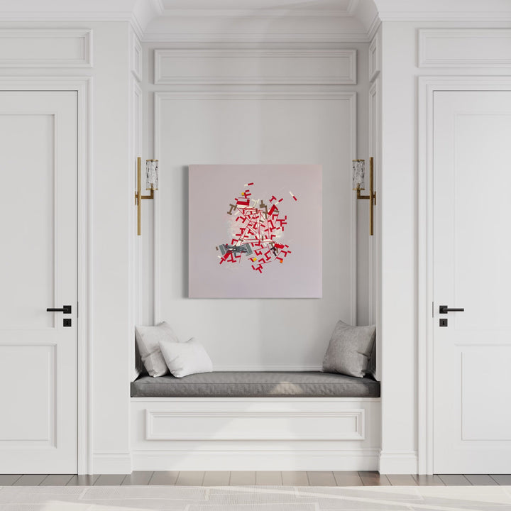 The artwork 'Iiiviarco' by Philippe Halaburda features an abstract composition with vibrant red geometric shapes and scattered elements against a soft grey background. The dynamic arrangement creates a burst-like pattern, with angular forms suggesting movement and energy. Displayed in a minimalist white interior setting, the 36x36 inch mixed media piece creates a striking focal point with its bold crimson patterns and contemporary aesthetic.