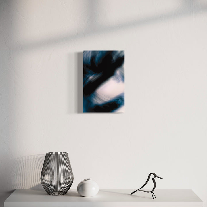 The artwork 'Indigo Dragon III' by Chunbum Park features swirling abstract forms in deep indigo blue and white, creating a dynamic, cloud-like composition. The digital photograph captures ethereal movement against a light background, framed with a clean white border and displayed above modern minimalist decor including ribbed vases and bird sculpture.