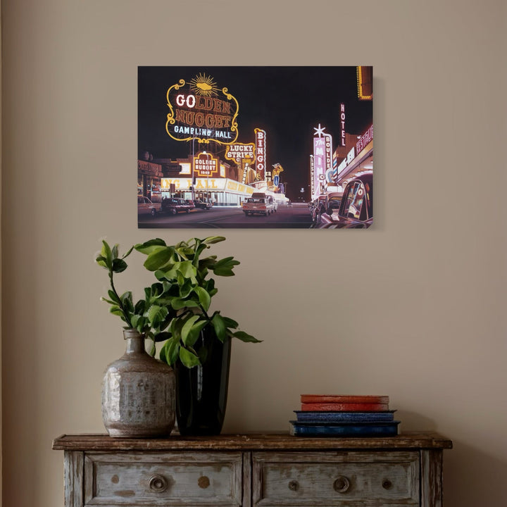 The artwork 'Las Vegas 1960' by Alex Devereux captures a vibrant nighttime scene of vintage Fremont Street, featuring iconic neon casino signs including the Golden Nugget. The 30x20 inch acrylic painting showcases illuminated marquees in yellows, reds, and whites against a dark sky, depicting classic Las Vegas streetscape and mid-century Americana architecture.