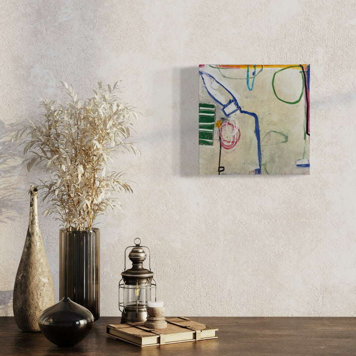 The artwork 'LS Series no. 5' by Janice La Motta features abstract linear compositions in vibrant blue, green, and pink oil stick strokes against a light neutral background on Yupo paper. The minimalist design shows loose geometric forms and spontaneous line work, creating a contemporary abstract expression mounted on a wall above decorative vases and lantern.