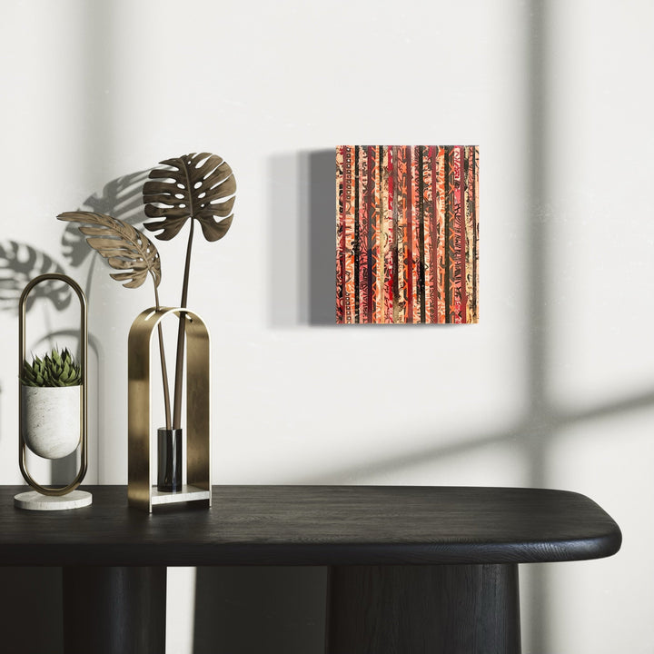 The artwork 'La Robe' by Nicole Hitchcock features vertical striped patterns in warm coral, bronze, and rust tones, created through layered collage technique sealed in glossy resin. The composition creates a textural, rhythmic effect reminiscent of weathered wood or vintage wallpaper, measuring 10 inches high by 8 inches wide.