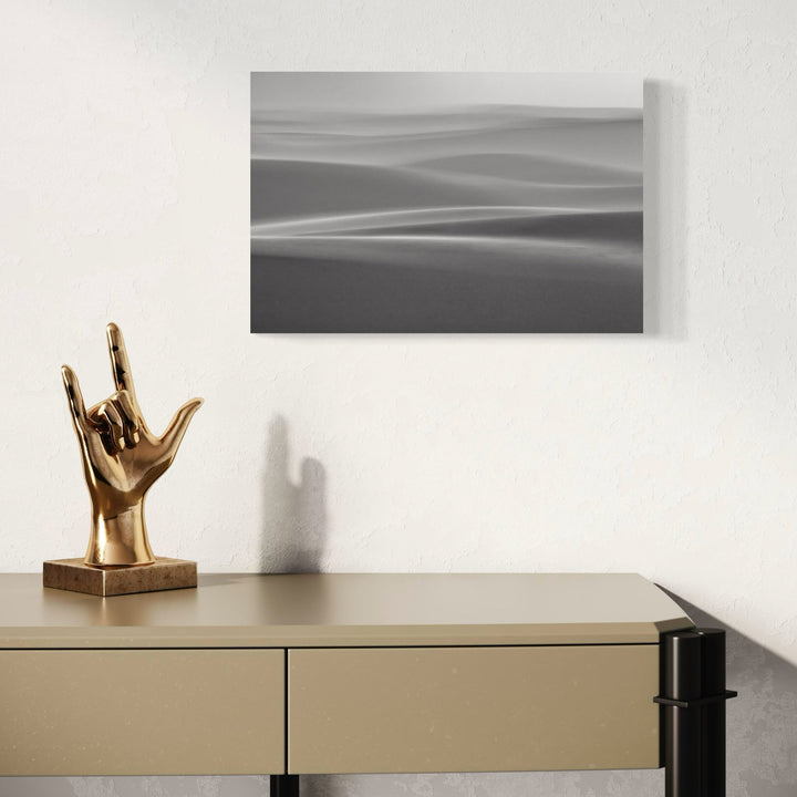 The artwork 'Magical Dunes' by Neil Shapiro features a minimalist black and white landscape photograph capturing ethereal rolling sand dunes. Soft, undulating lines create a dreamlike abstract composition with gentle gradients transitioning from light to dark tones. The textured Hahnemuhle print enhances the atmospheric quality of these mystic desert forms.