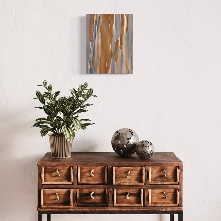 The artwork 'Ochre Eucalyptus' by Taylor Stoneman features vertical flowing brushstrokes in warm ochre and cool gray tones on linen canvas. The abstract composition suggests organic movement reminiscent of eucalyptus bark textures, painted in oil with loose, expressive strokes. The 14x11 inch piece displays a harmonious balance between earth tones and metallic accents.