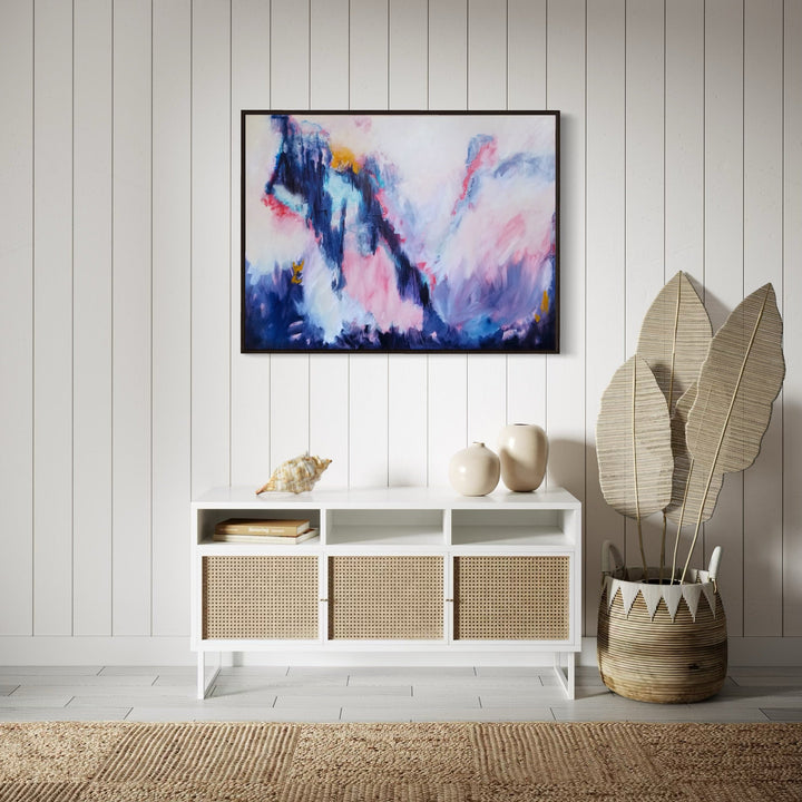 The artwork 'Passion's Pulse' by Janyce Erlich-Moss features a dynamic abstract composition with sweeping strokes of deep navy blues intersecting with ethereal pink and white clouds. Dramatic brushwork creates a mountainous landscape effect, with touches of golden light breaking through the moody atmosphere. Acrylic on canvas, 31x41 inches, showcasing expressive contemporary style.