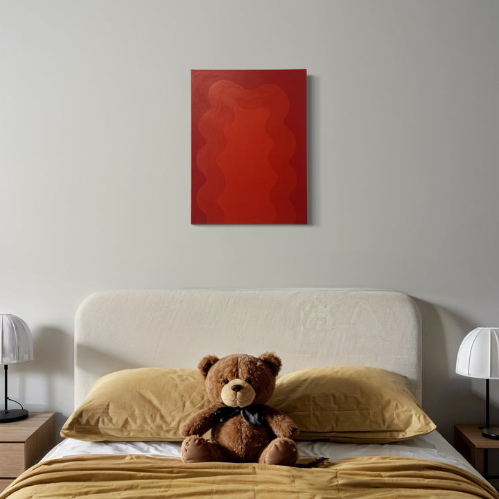 The artwork 'Red' by Shadia Sabagh features bold monochromatic red tones with subtle organic wave patterns on canvas. The abstract acrylic painting displays varying shades and textures of red, creating a dynamic and fluid composition. Contemporary minimalist artwork shown mounted above a bed with neutral decor. Energy of Color Series, 24x18 inches. By Shadia Sabagh.