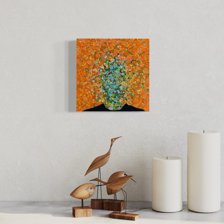 The artwork 'Scattered' by Matthew Cramer features an abstract composition of vibrant turquoise and blue dots exploding outward against a warm orange background. The pointillistic style creates a dynamic burst effect on the 12x12 inch oil canvas, with small circular elements radiating from a central cluster, reminiscent of a cosmic explosion or blooming flowers.