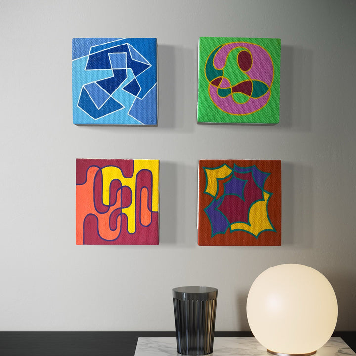 The artwork 'Seasonal Phenomena IV' by Joe Piscopia features four vibrant abstract square canvases arranged in a grid pattern. Each 13-inch panel showcases distinct geometric shapes: angular blue forms on light blue, curved pink and brown shapes on green, wavy purple patterns on orange-red, and bold yellow-blue abstract forms on rust brown. Acrylic on canvas.