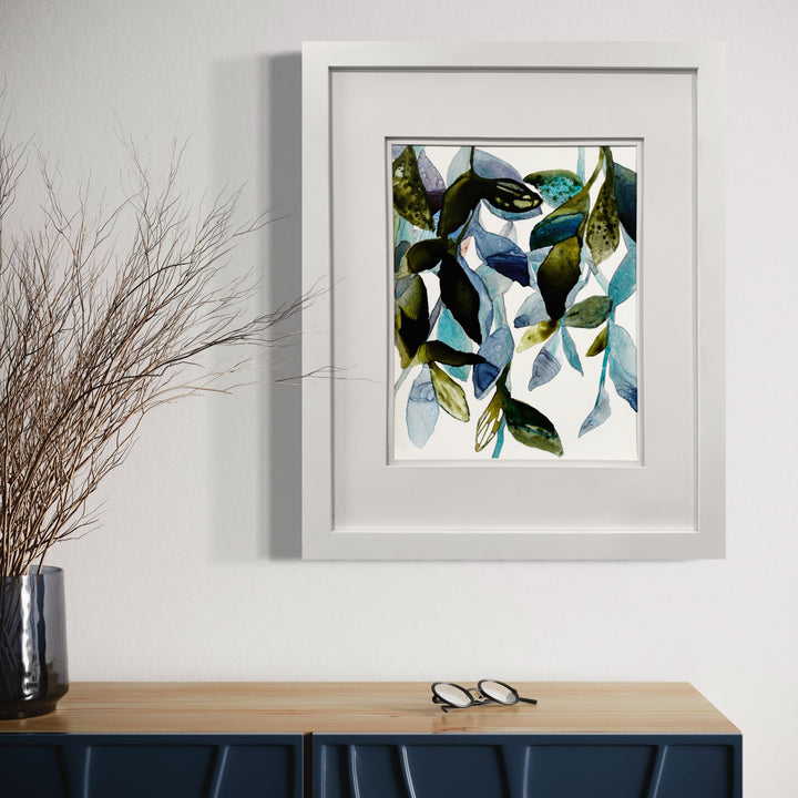 The artwork 'Something Blue II' by Rachel Kohn features an abstract composition of flowing organic shapes in watercolor and ink on yupo paper. Translucent leaves and petals in shades of turquoise, navy, and olive green create a dynamic, fluid movement across the white surface. The delicate brushwork and layered transparency showcase the unique properties of watercolor on synthetic paper. By Rachel Kohn.