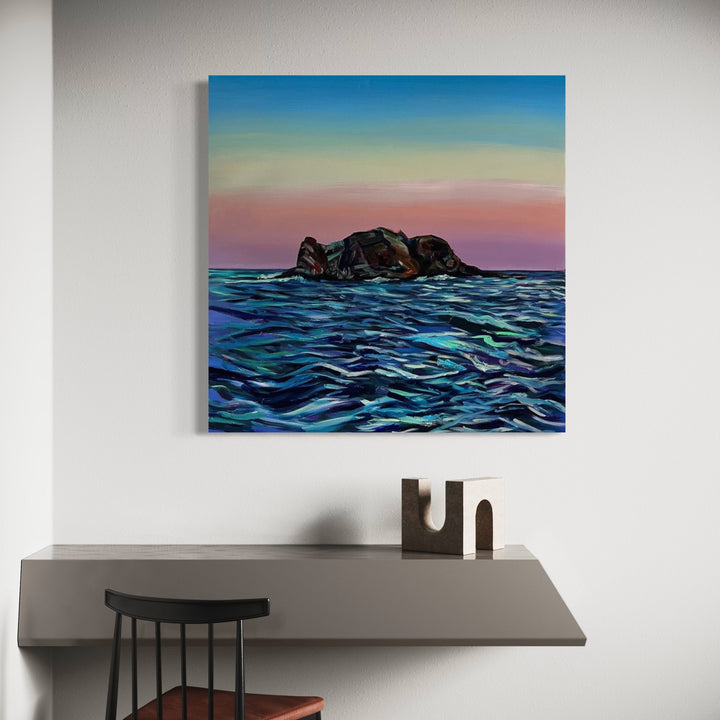 The artwork 'Sorbet Elephant' by Claudia Robles-Gil depicts a dark rocky island formation emerging from dynamic turquoise waters beneath a gradient sky of blue, yellow, and pink hues. The seascape features expressive brushstrokes creating textured waves in deep blues and teals, while the sunset atmosphere evokes a serene coastal mood. Oil and acrylic on 40x40 inch canvas.