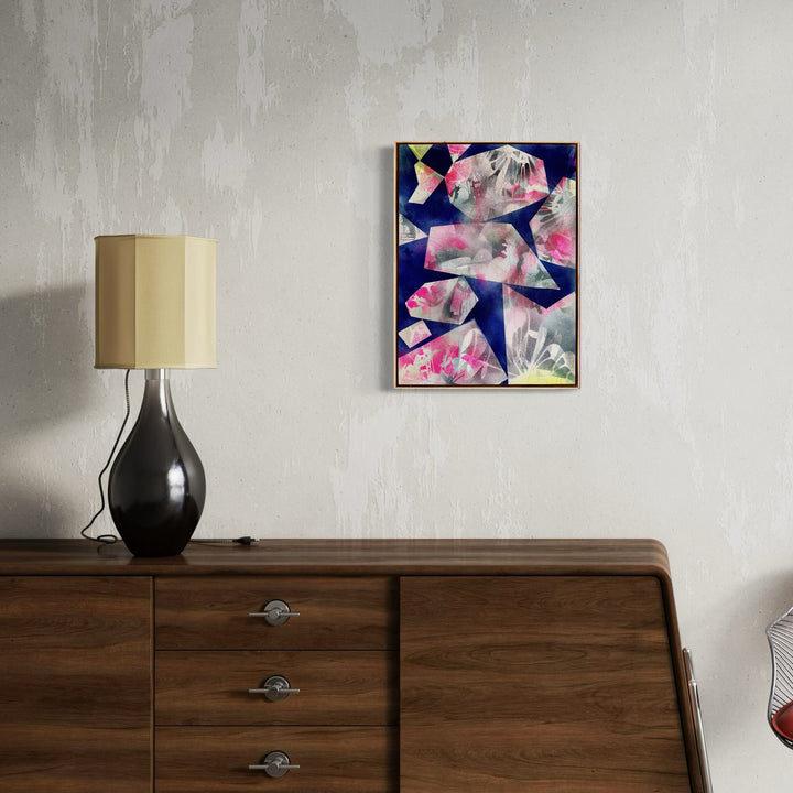 The artwork 'Sun Set' by Ann Tarantino features abstract geometric fragments in vibrant pink and white tones against a deep navy blue background, creating a dynamic composition on a laser-etched acrylic panel. The angular shapes appear to float and intersect, reminiscent of crystal formations or shattered glass, measuring 24 x 18 inches by Ann Tarantino.