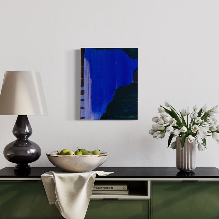 The artwork 'The Blue Hour (violet)' by Cora Jane Glasser features a striking abstract composition with a bold electric blue expanse meeting dark geometric shapes. Oil on linen creates rich textural depth, while the dramatic contrast between deep navy and black forms suggests an urban landscape at twilight. The 20x16 inch painting captures the essence of dusk's mysterious ambiance.