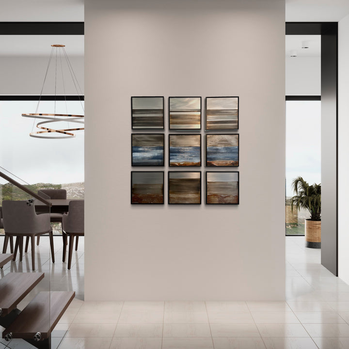 The artwork 'Where Land Meets Sky 9' features nine square panels arranged in a 3x3 grid, showcasing abstract landscapes with earthy browns, moody grays, and ethereal blues. Each panel captures the atmospheric transition between earth and sky through textured mixed media on steel, creating a harmonious modern composition by Nicki Adani.