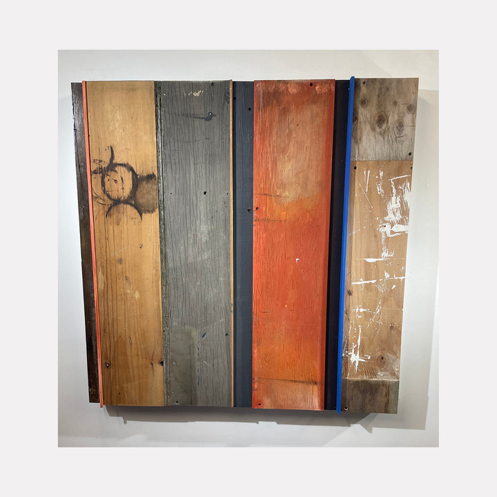 The artwork '36-02' by Simon Draper features a geometric assemblage of vertical wooden panels in contrasting colors: natural pine, weathered gray, rustic orange, and distressed brown. The panels display a raw, industrial aesthetic with visible textures, scratches, and paint marks, creating a minimalist composition within a 36x36 inch square format.