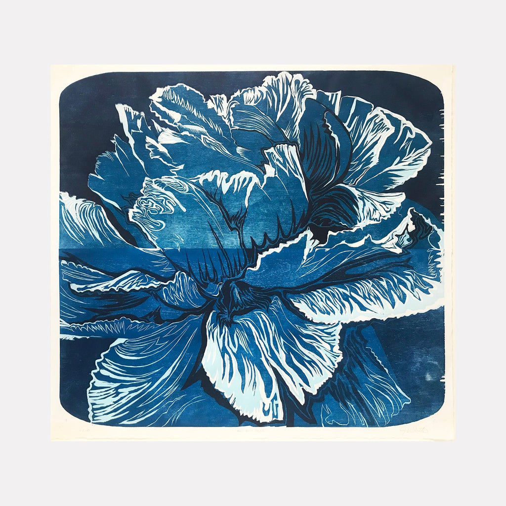 The artwork 'All But Blue' by Jeff White features a dramatic close-up of a blooming flower rendered in deep indigo and white tones. The reduction woodcut technique creates bold contrasts between the delicate, rippling petals and negative space. The handmade kozo paper adds textural depth to this striking botanical print in a contemporary woodblock style.