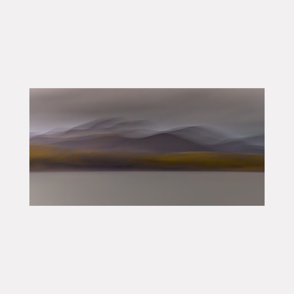 The artwork 'Iceland Highlands' by Neil Shapiro captures a minimalist landscape featuring misty mountain ranges in muted purple-grey tones, with a golden ochre plain beneath. The composition creates a dreamlike atmosphere through soft, blurred transitions between layers, printed on textured Hahnemuhle paper for enhanced depth and quality.