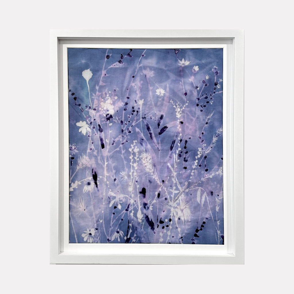 The artwork 'Iced Sky II' by Rachel Kohn features delicate botanical silhouettes against a dreamy twilight blue background. Ethereal white flowers and stems create a frost-like pattern, while deep indigo spots and marks scatter throughout the composition. The dye and bleach technique on cotton creates a luminous, crystalline effect reminiscent of a winter garden at dusk.