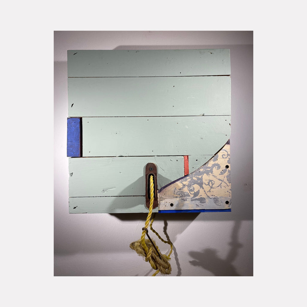 The artwork 'Kingston Shutter no. 30' by Simon Draper features a minimalist wood assemblage with pale mint-green horizontal planks, accented by cobalt blue trim and a decorative patterned corner piece. A weathered brass hook with frayed rope adds rustic detail to this 16x16 painted wood construction, creating an abstract composition that merges architectural and nautical elements.