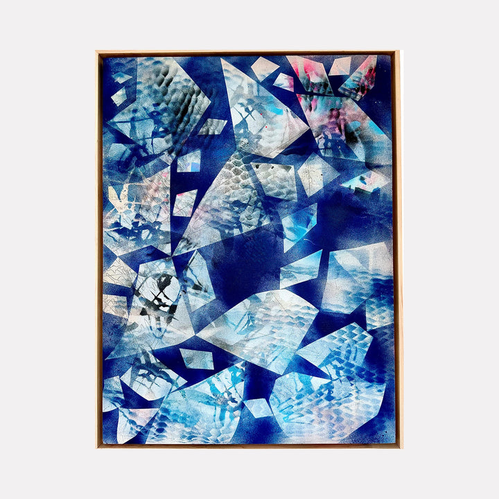 The artwork 'New Blue' by Ann Tarantino features an abstract composition of fractured geometric shapes in varying shades of deep and light blue. Angular fragments create a dynamic mosaic pattern, resembling shattered ice or crystal formations. The laser-etched acrylic panel adds textural depth, with translucent overlapping elements creating a sense of movement and dimension against a navy background.