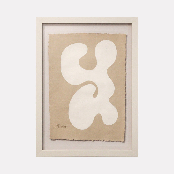 The artwork 'Serenity III' by Shadia Sabagh features an organic abstract form in white against a soft beige background, flowing in a curvilinear shape reminiscent of a fluid or biomorphic design. Created with acrylic paint on handmade cotton paper, the minimalist composition showcases smooth edges and graceful curves within a white frame, expressing tranquil movement.