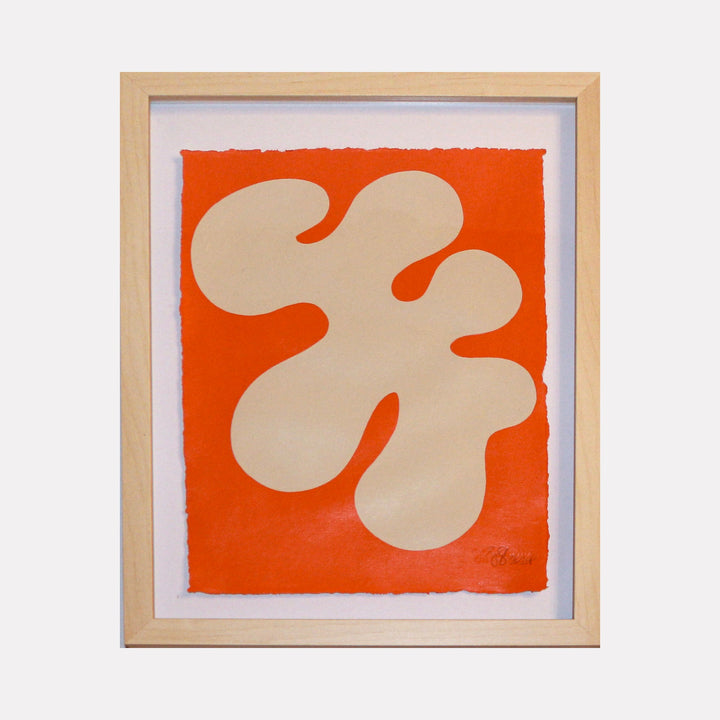 The artwork 'Stillness II' by Shadia Sabagh features an abstract organic shape in cream against a vibrant orange background. The flowing, biomorphic form resembles a cloud or amoeba-like figure, painted with acrylic on handmade cotton paper with deckled edges, framed in natural wood. The minimalist composition creates a sense of tranquility and balance.