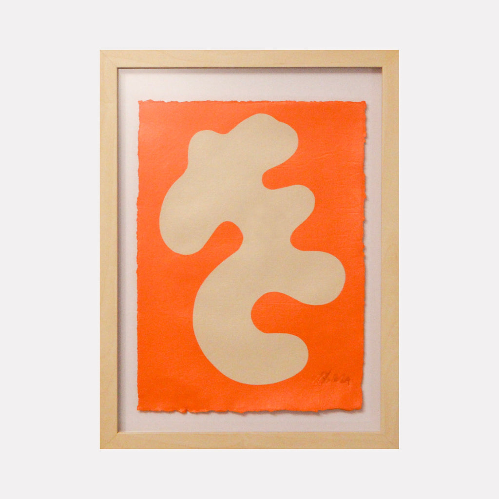 The artwork 'Stillness III' by Shadia Sabagh features an abstract organic shape in cream against a vibrant orange background, painted in acrylic on handmade cotton paper. The flowing, biomorphic form creates a striking contrast with its bold background, framed in natural wood, showcasing minimalist contemporary design principles.