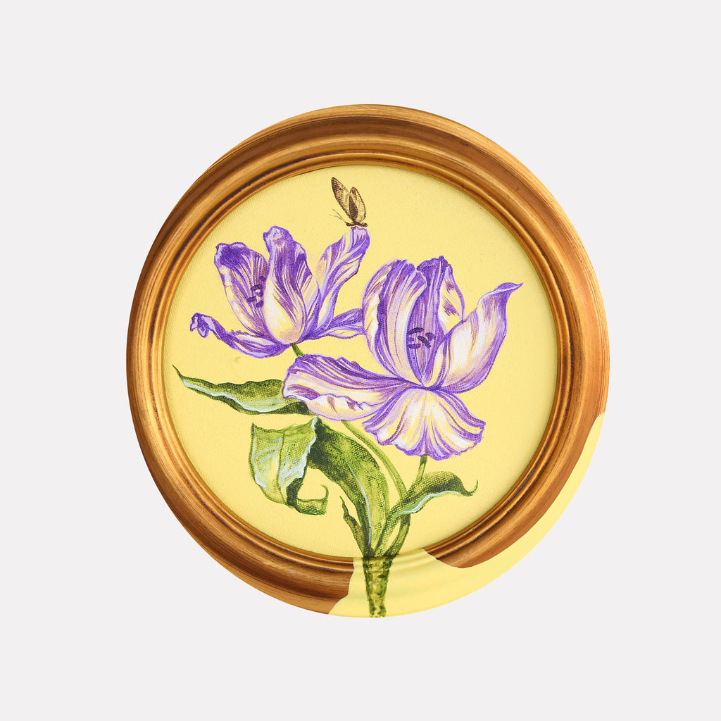 The artwork 'The Walk of the Butterfly' by Carlos Gamez de Francisco features delicate purple iris flowers with detailed petals against a warm yellow background. A small golden butterfly hovers above. The circular composition is framed by an elegant gold border. The 8x8 inch acrylic painting showcases botanical realism with vibrant colors and precise brushwork.