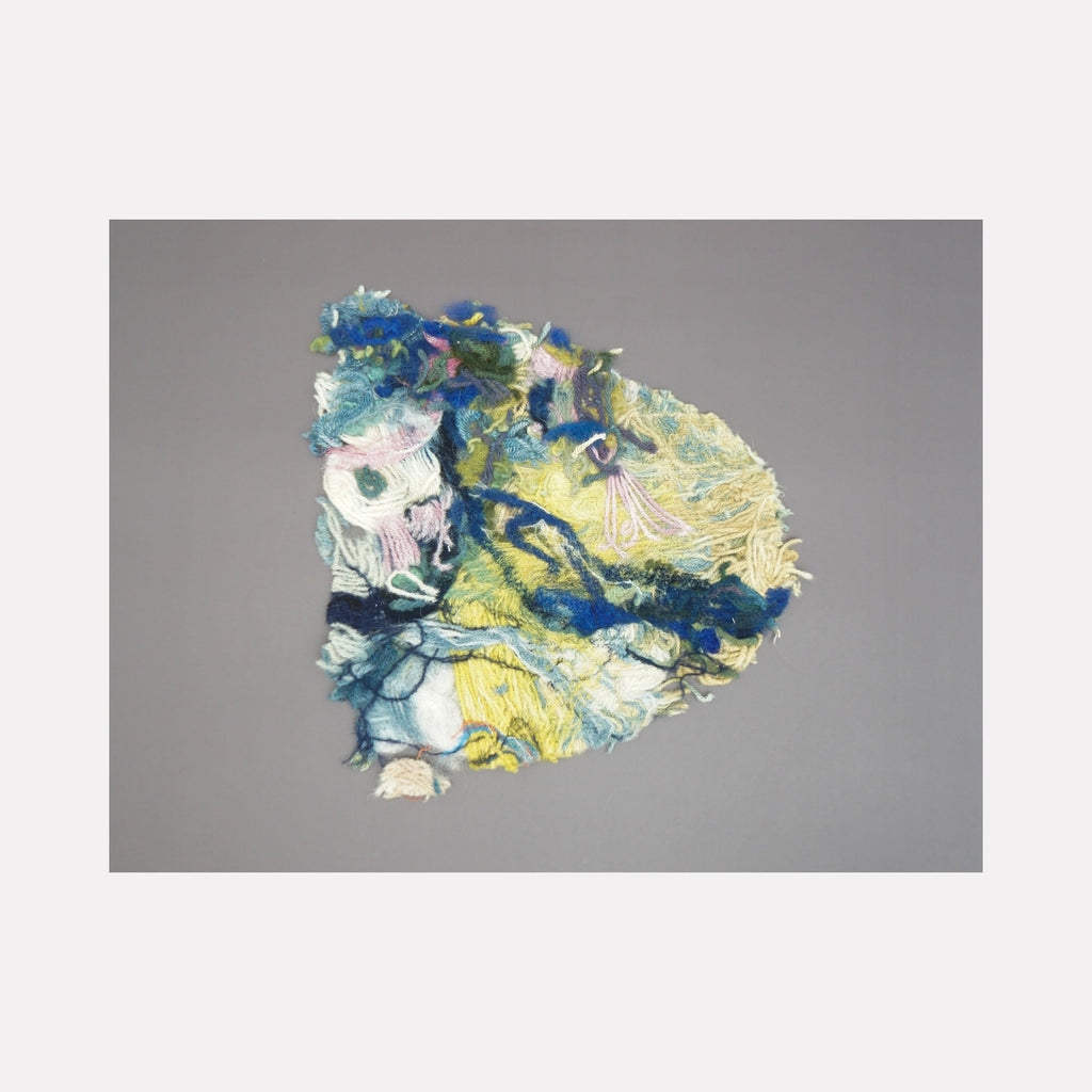 The artwork 'Untitled 174' by Victoria Manganiello features a textural abstract composition blending vibrant blues, yellows, and white fibers. The piece showcases intertwined natural and synthetic materials creating an organic, cloud-like form against a neutral gray background, demonstrating intricate fiber art techniques at 12x12 inches.