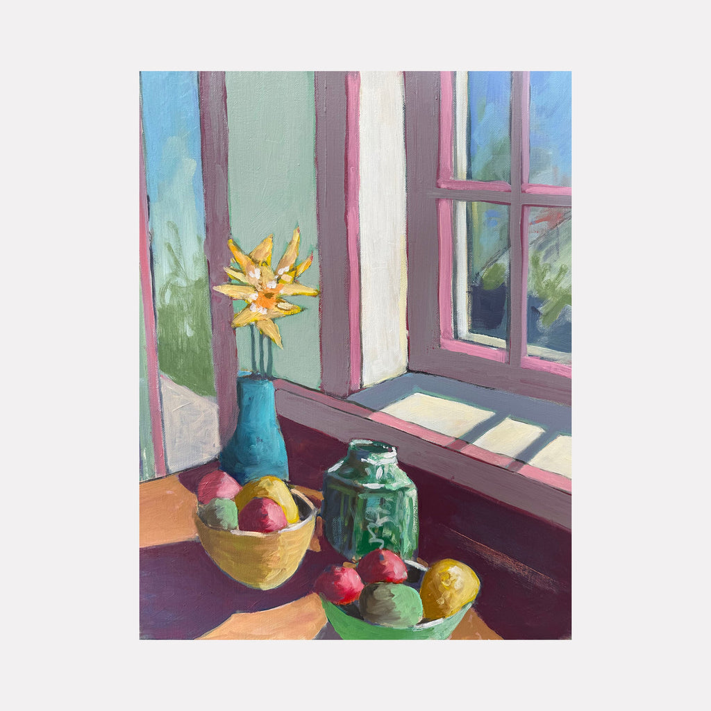 The artwork 'Window Light' by Roger McErlane depicts a sunlit still life arrangement featuring a blue vase with vibrant yellow daisies, set alongside two bowls of colorful fruits and a green glass jar on a wooden surface near a window. The scene captures warm natural light filtering through pink-framed windows, creating a serene domestic atmosphere with soft sage green walls.