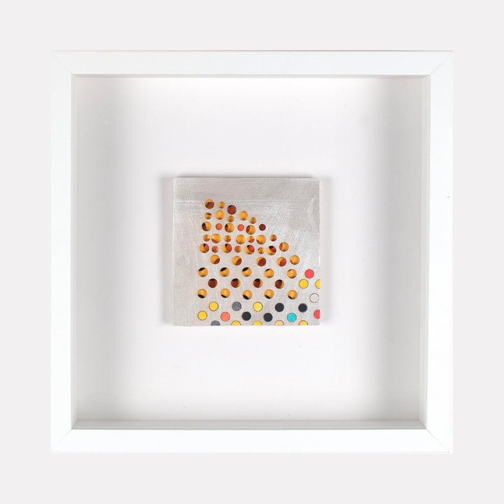 The artwork 'Bissett' by Margaret Griffith features a minimalist geometric pattern of scattered dots in orange, yellow, pink, and blue tones against a light gray background. The acrylic on cut paper piece displays a gradient-like arrangement of circular forms, densely clustered in one corner and dispersing outward, creating a dynamic visual flow.