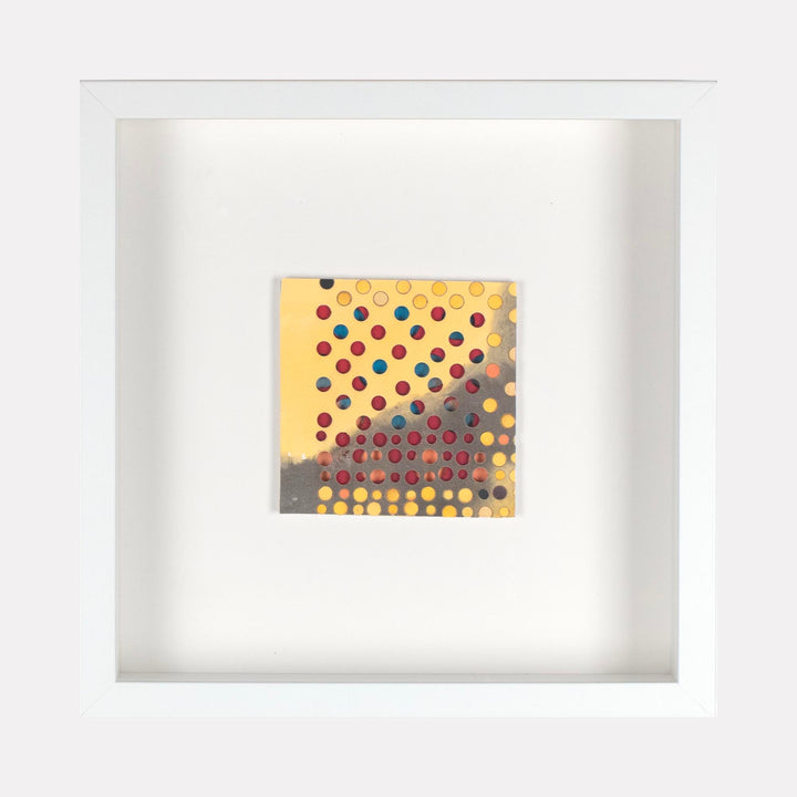 The artwork 'Kelly' by Margaret Griffith features a geometric pattern of colorful polka dots on a yellow and gray gradient background. The dots transition from vibrant red, blue, and purple circles against a warm yellow surface to a shadowy gray base, creating a modern abstract composition in acrylic on cut paper, framed in white.