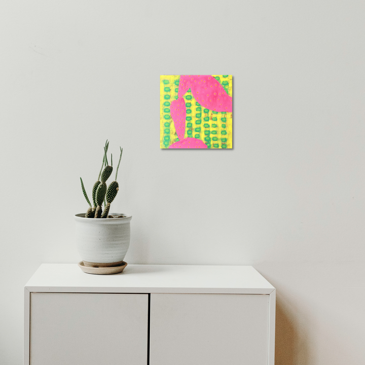 Composition No. 53 by Raul Ortiz features vibrant neon pink background with geometric lime green grid patterns creating a dynamic contemporary abstract design. Acrylic on linen artwork displayed above white modern furniture with potted cactus, showcasing minimalist aesthetic in 12x12 inch format.