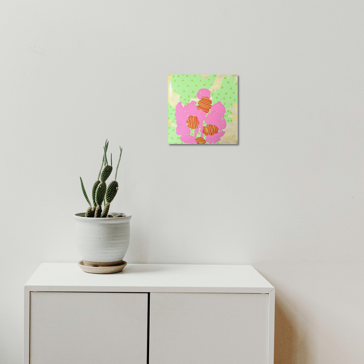 The artwork 'Composition No. 64' by Raul Ortiz features a playful abstract design with a large pink organic shape resembling a flower against a mint green polka-dotted background. Small orange-striped geometric elements accent the composition, creating a whimsical and modern aesthetic on linen canvas. Acrylic painting, 12x12 inches by Raul Ortiz.