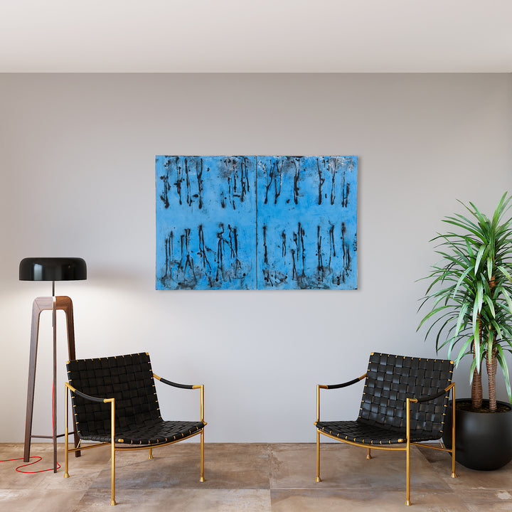 The artwork 'Ditto Dyptic' by Shira Toren features a striking diptych composition in vibrant azure blue with abstract vertical drip patterns in deep black. The Venetian plaster creates rich textural elements across two symmetrical panels, suggesting a rhythmic forest-like pattern against the bright background. 40x60 inches canvas.